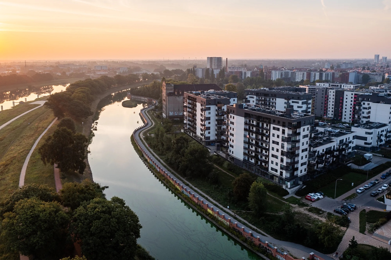 Rzeka i osiedla Wrocławia z lotu ptaka o zachodzie słońca.